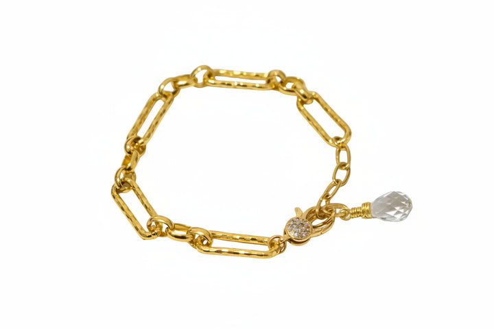 Gold chain bracelet with a clear crystal charm on a white background