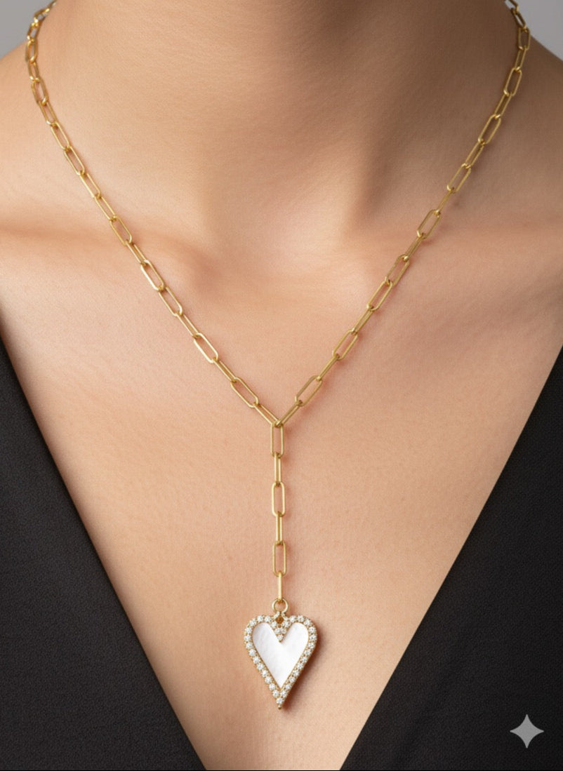 Gold chain necklace with a heart-shaped pendant on a person wearing a black top.